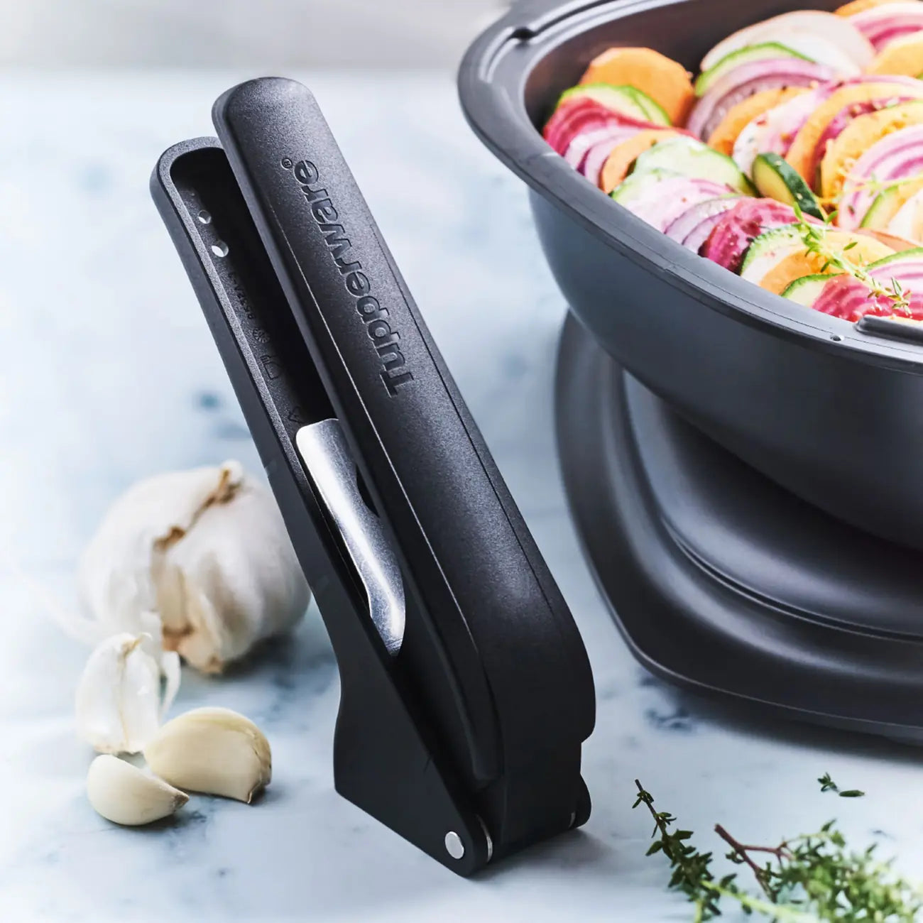 Knoblauchpresse Knobi-Star von der Marke Tupperware / Drei in Eins Küchenwerkzeug / zum Schälen und Pressen von Knoblauch / mit Kräuterentblätterungsfunktion / mit Ergonomischen Griff / Einfach zu Reinigen / Hier direkt online kaufen 