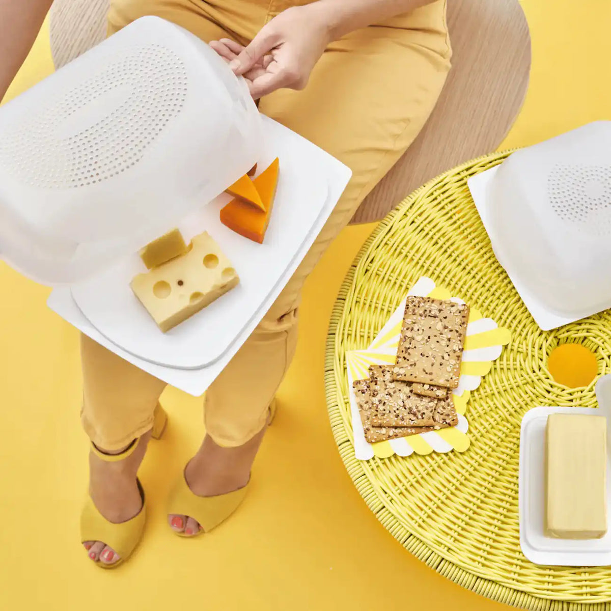 Tupperware Junior KäseMaX geöffnet in der Hand: Käsewürfel und Emmentaler auf dem Tablett, weiterer KäseMaX auf dem Tisch