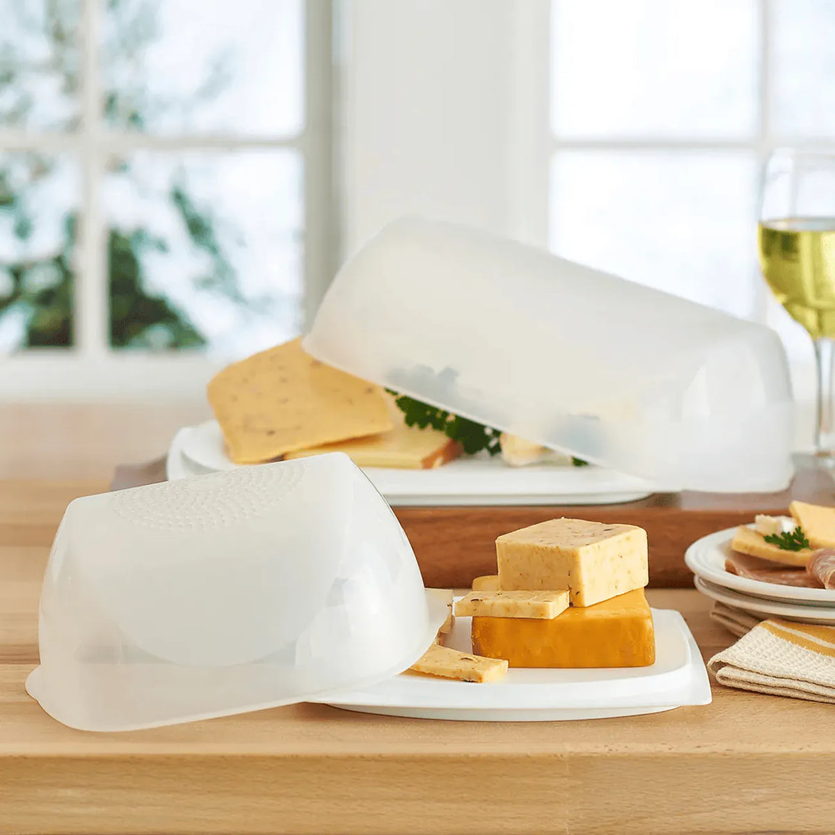 Tupperware Junior KäseMaX mit Cheddar und Kräuterkäse auf der Küchentheke, dahinter großer KäseMaX mit Käseplatte