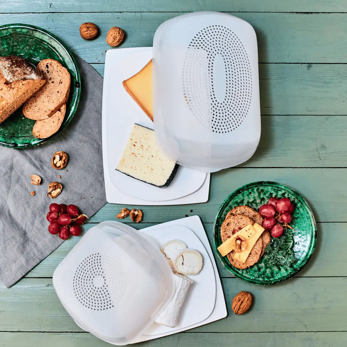 Tupperware Junior KäseMaX und KäseMaX mit verschiedenen Käsesorten, Brot, Trauben und Walnüssen auf Holztisch