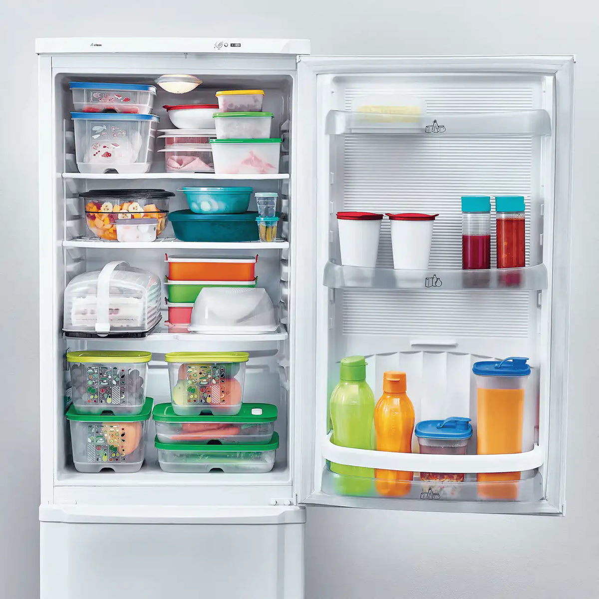 Tupperware Junior KäseMaX im gefüllten Kühlschrank zwischen Tupperware Behältern, Flaschen und Frischhalteboxen