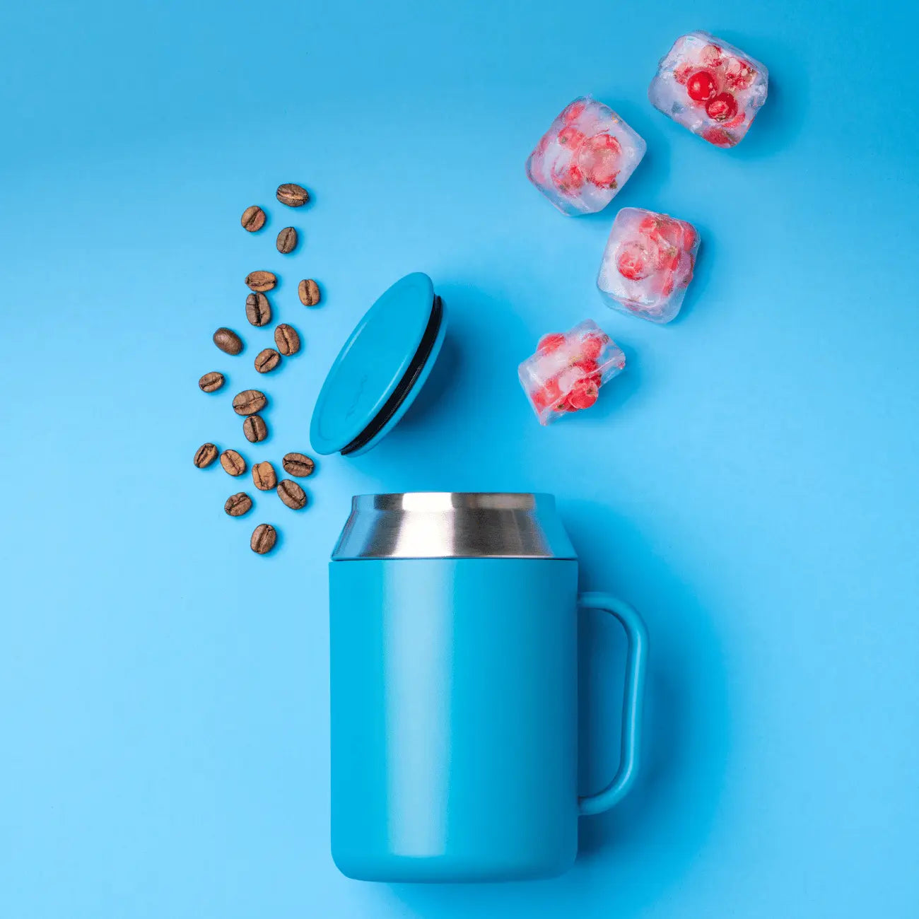Isobecher 400ml von der Marke Tupperware / aus hochwertigem Edelstahl / Perfekt für Büro oder Home Office / mit Ergonomischen Griff / mit passendem Deckel / Beispielbild Becher liegend mit Kaffeebohnen Trapiert / Hier direkt online kaufen