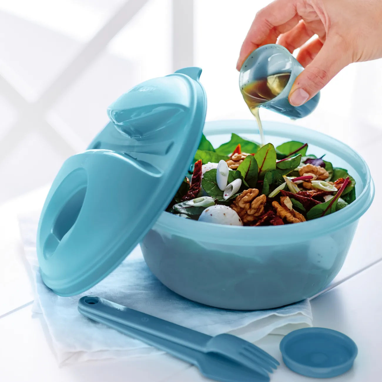 Salat To Go 1,4l Essential von der Marke Tupperware / zum Mitnehmen von Salat, Snacks und Ähnlichen / mit Besteck Halterung am Deckel / Extra Behälter für das Dressing / Perfekt für Picknick und Mittagspause / Beispielbild Salat Dressing im Extra Behälter / Hier direkt online kaufen 